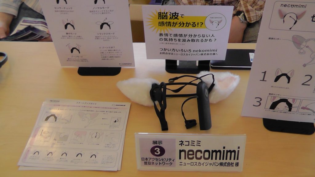 necomimiの展示ブースの写真。カチューシャに猫耳を模したものを付けたようなガジェットが置かれていて、付けた人の感情によって猫耳が動くという説明がされている。