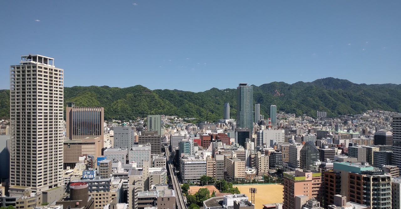 高いビルから外を眺めた写真。天気が良く、神戸の山々が見えている。